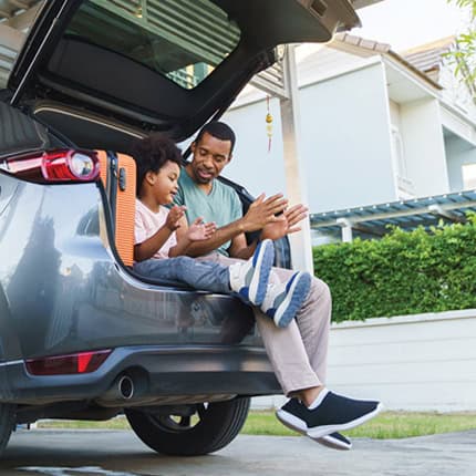 father and son sitting in trunk of car